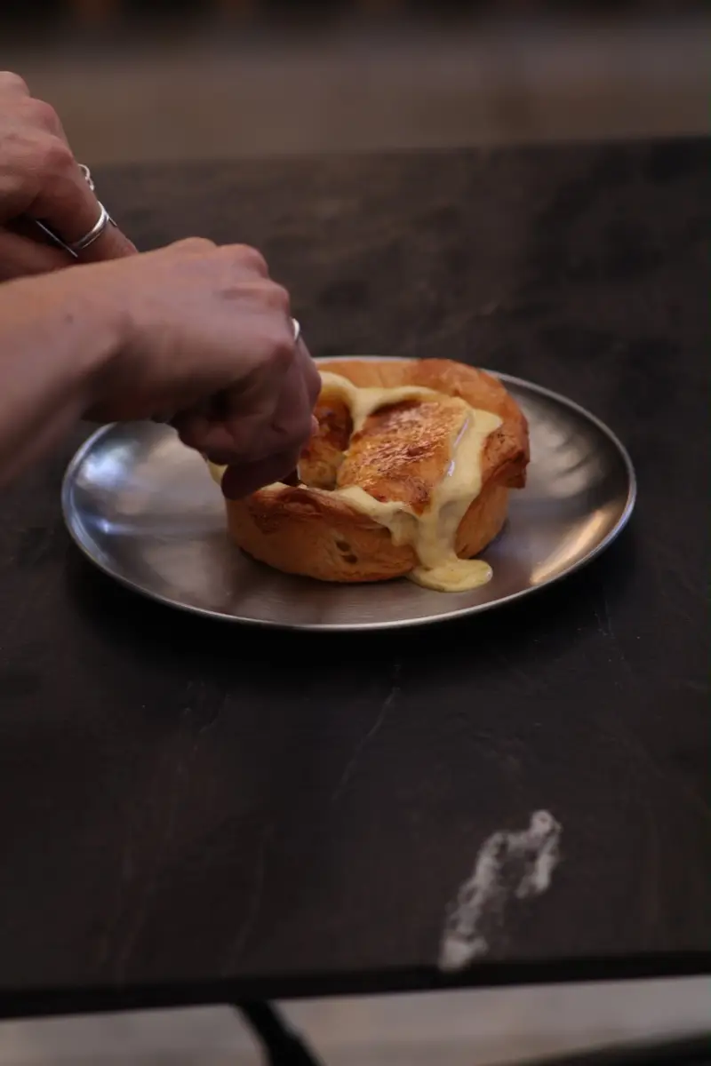 Pieza de laminado con crema quemada al soplete, servida en plato de acero sobre mármol negro